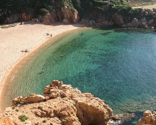 Li Cossi auf Sardinien: Die wunderschöne Bucht mit smaragdgrünem und glasklarem Wasser ist von roséfarbenden Felsen und grünen Macchia-Gewächs umringt.