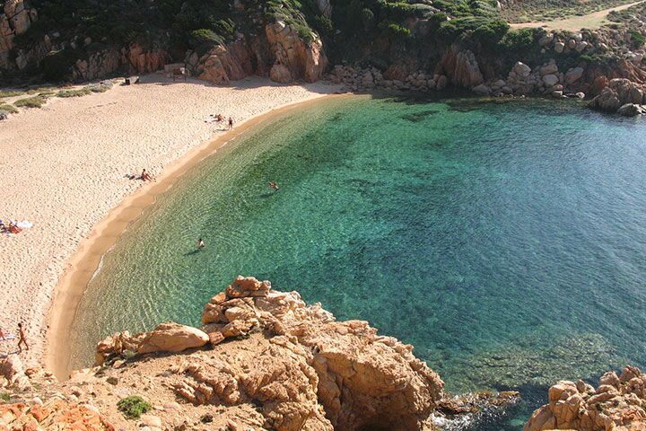 Li Cossi auf Sardinien: Die wunderschöne Bucht mit smaragdgrünem und glasklarem Wasser ist von roséfarbenden Felsen und grünen Macchia-Gewächs umringt.